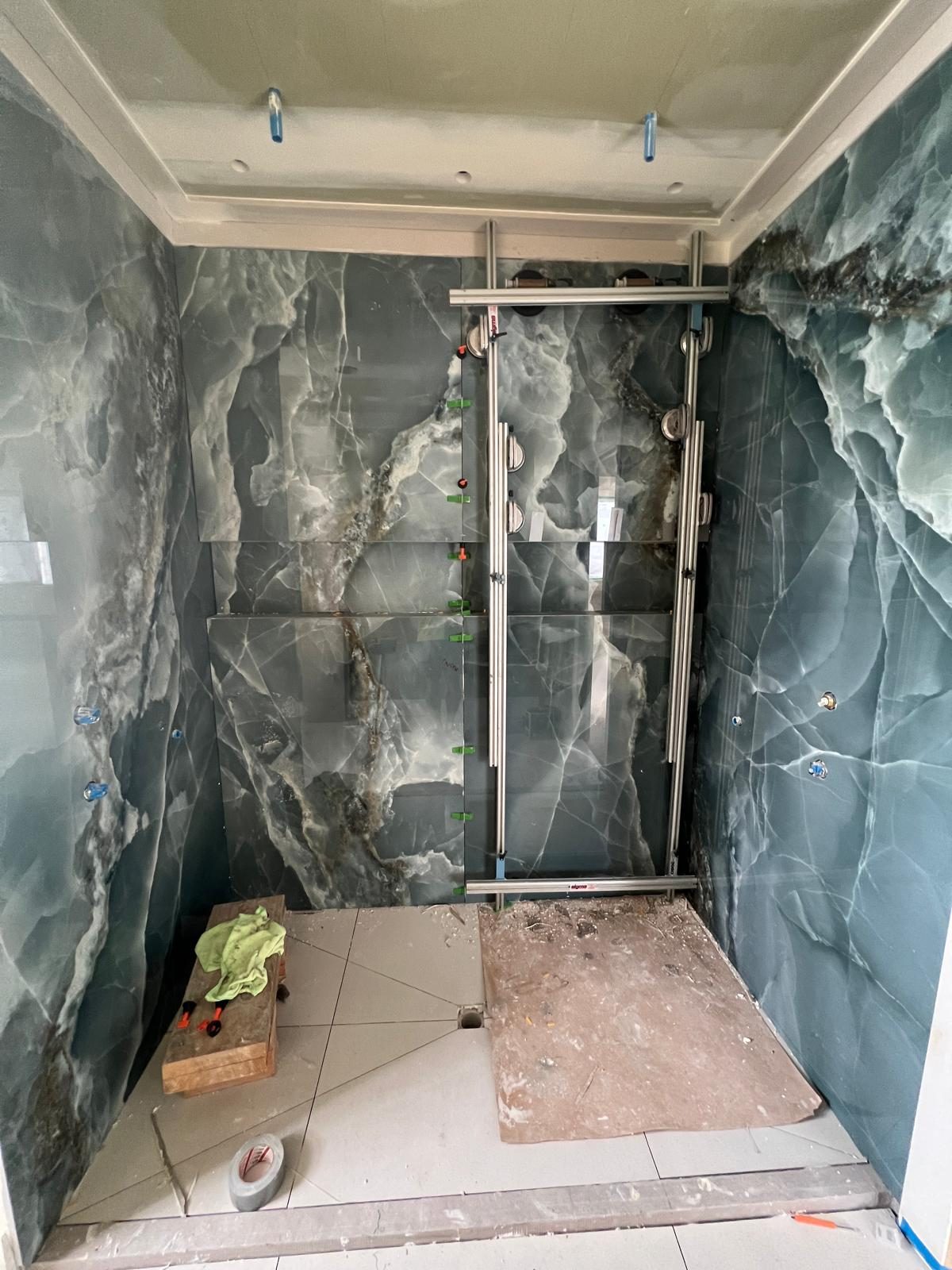 Green onyx-look porcelain slabs braced during shower installation