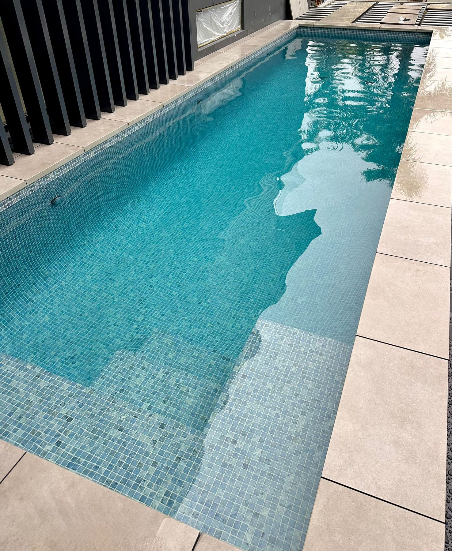 Glass mosaic lap pool with porcelain paver surrounds