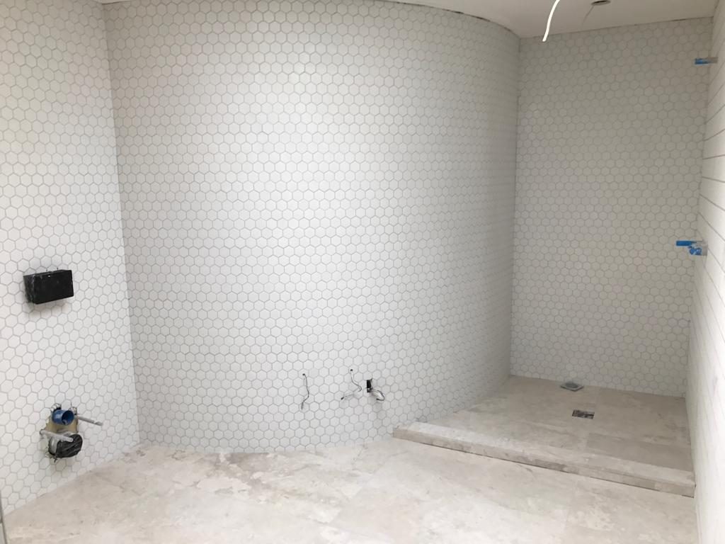 Curved bathroom wall finished in white hexagon mosaic
