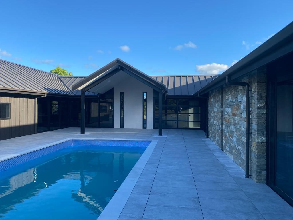 Finished pool with schist wall and porcelain pavers on a rural property
