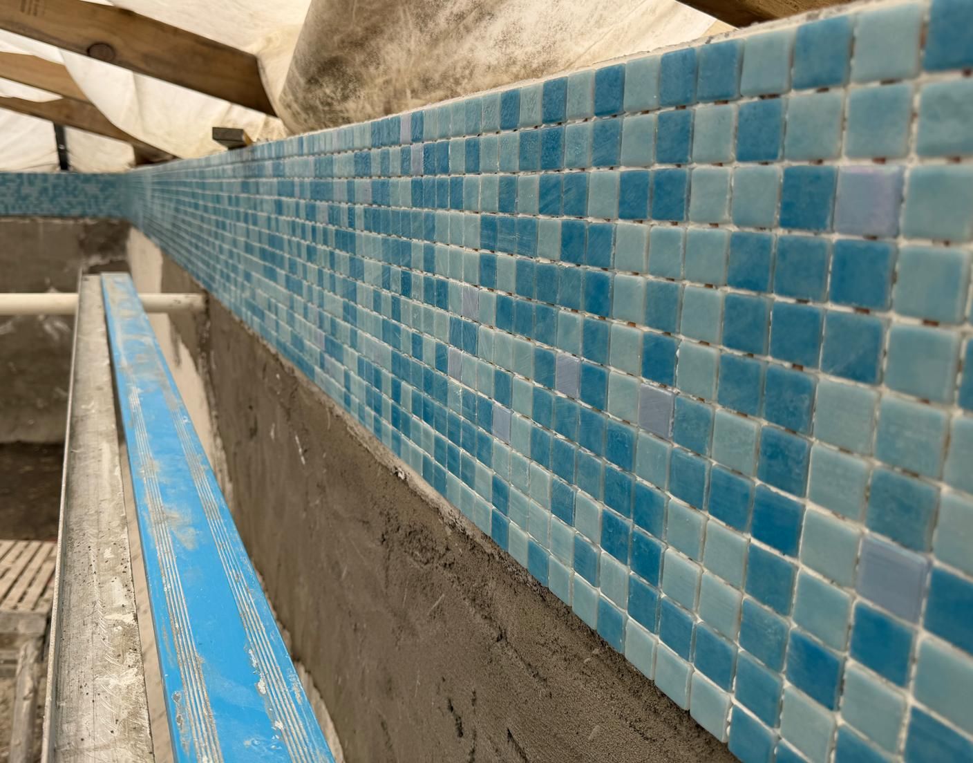 Trend glass mosaic blend being installed along a pool waterline