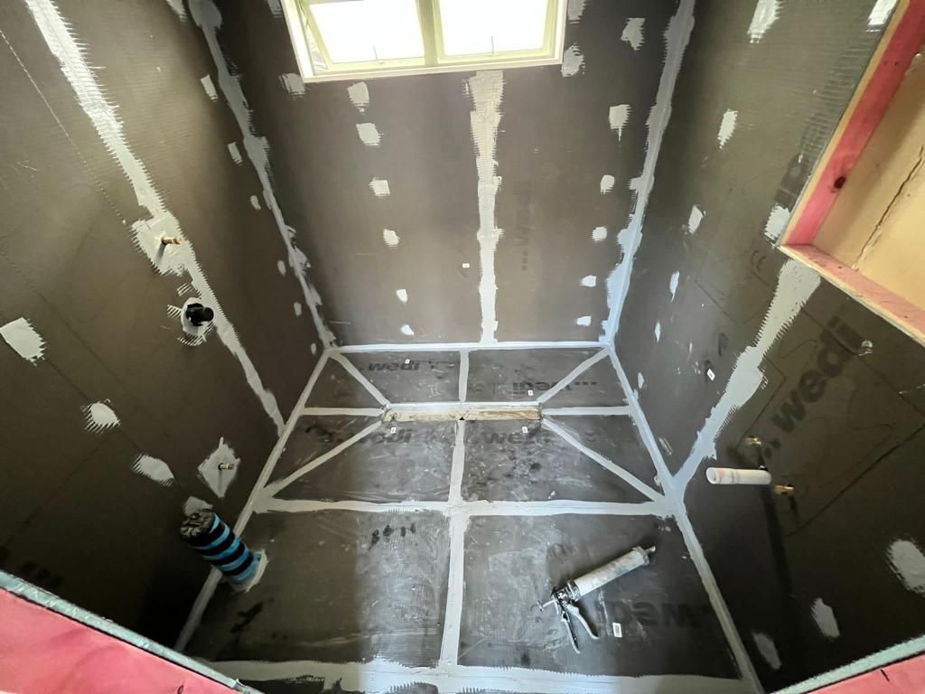 Top-down view of a Wedi wet room — sealed floor panels and linear drain before tiling